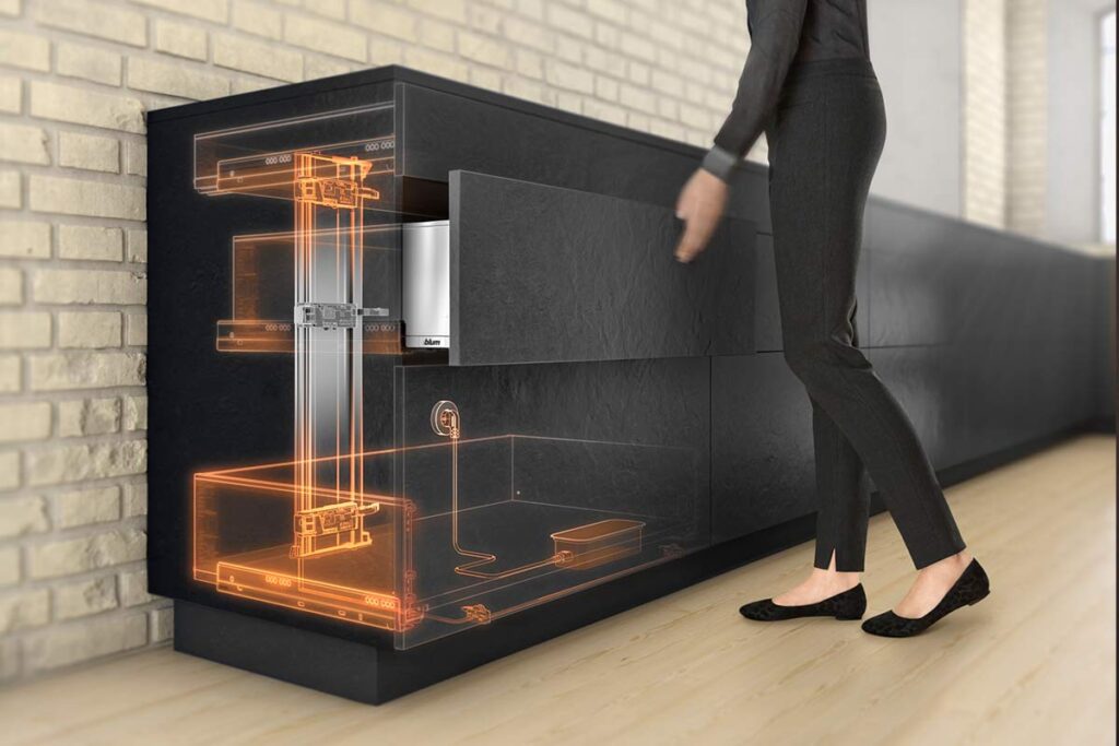 Usuario activando el sistema de asistencia eléctrica SERVO-DRIVE de Blum mediante un ligero toque para apertura automática en cocina Hauska.